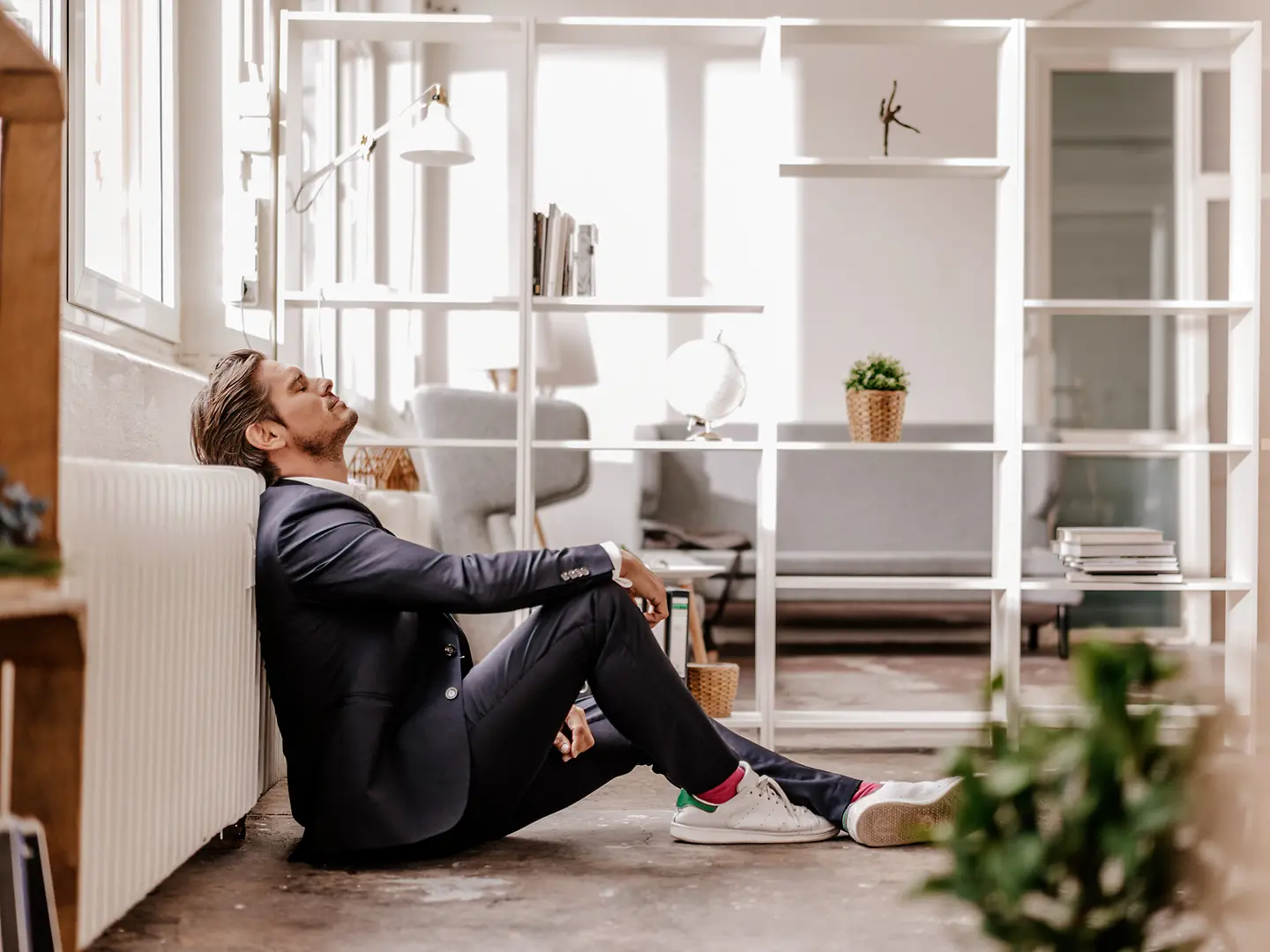 Mann im Anzug sitzt auf dem Fußboden seines Büros