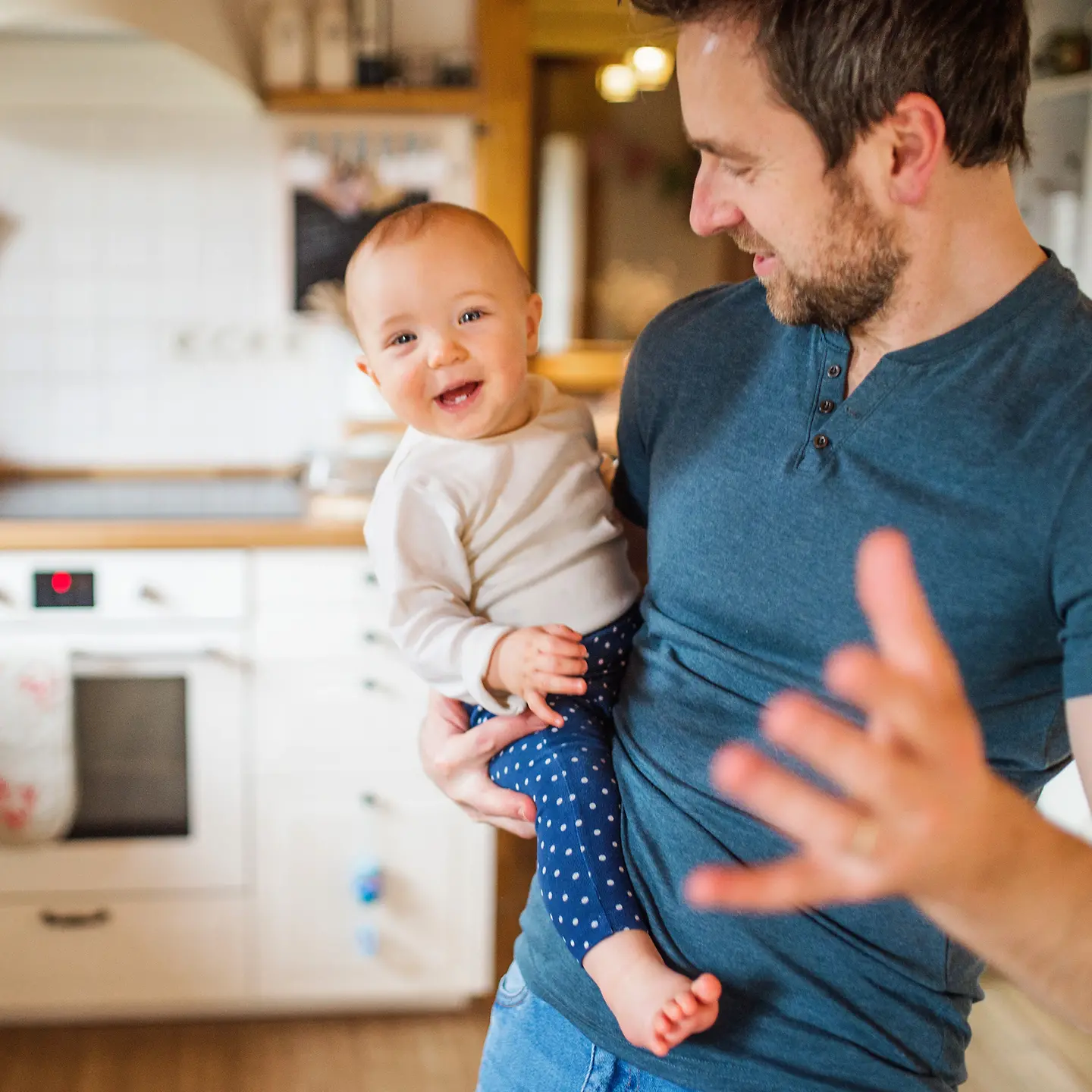 Ein Vater steht in der Küche und hält ein Baby auf dem Arm