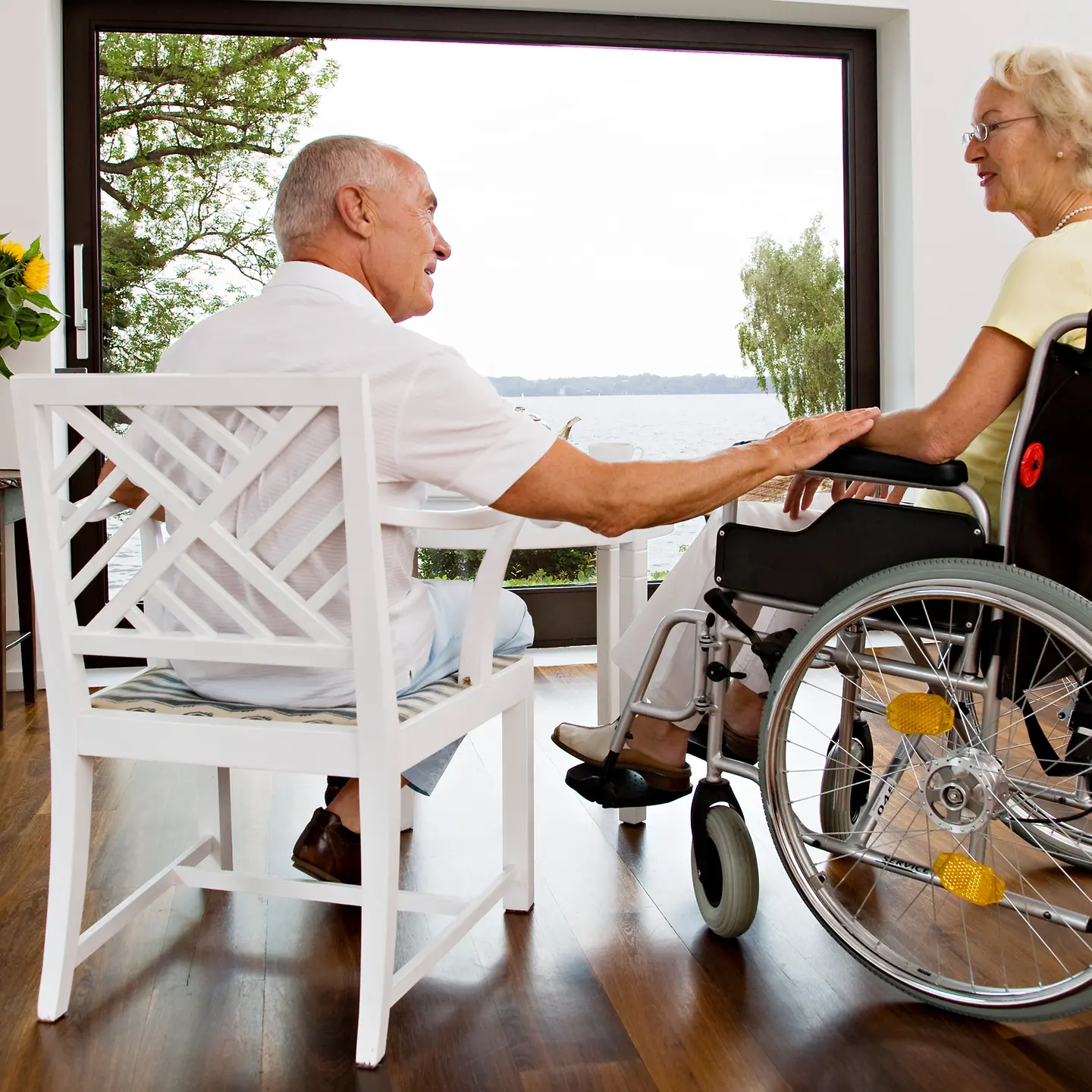 Älterer Mann und Ehefrau im Rollstuhl sitzen im barrierefreien Wohnzimmer